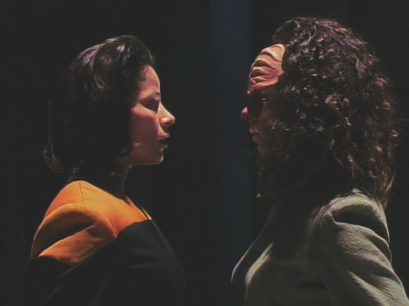 Život jí zachraňuje klingonská B'Elanna, která ji našla. Obě dvě se skrývají v tunelech dolů. Klingonka se chce probít ven, lidská B'Elanna chce raději vypnout silové pole. 