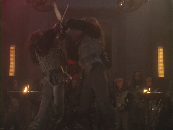 Worf Gowrona vyzval a bojuje s ním na život a na smrt. Martok zatím zabránil Odovi, aby se vrátil do haly, a Odo si uvědomuje, že měňavec není Gowron, nýbrž generál.
