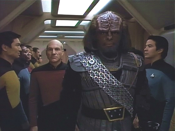 Dojatý Worf prochází v doprovodu kapitána čestným špalírem do transportní místnosti.