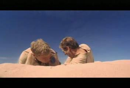 Archer a Trip se zahrabali do písku, aby se nestali terčem ostřelování.