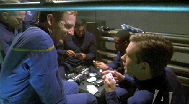 Kapitán obhlíží svou posádku, v tomto případě skupinu krátící si chvíli pokerem.