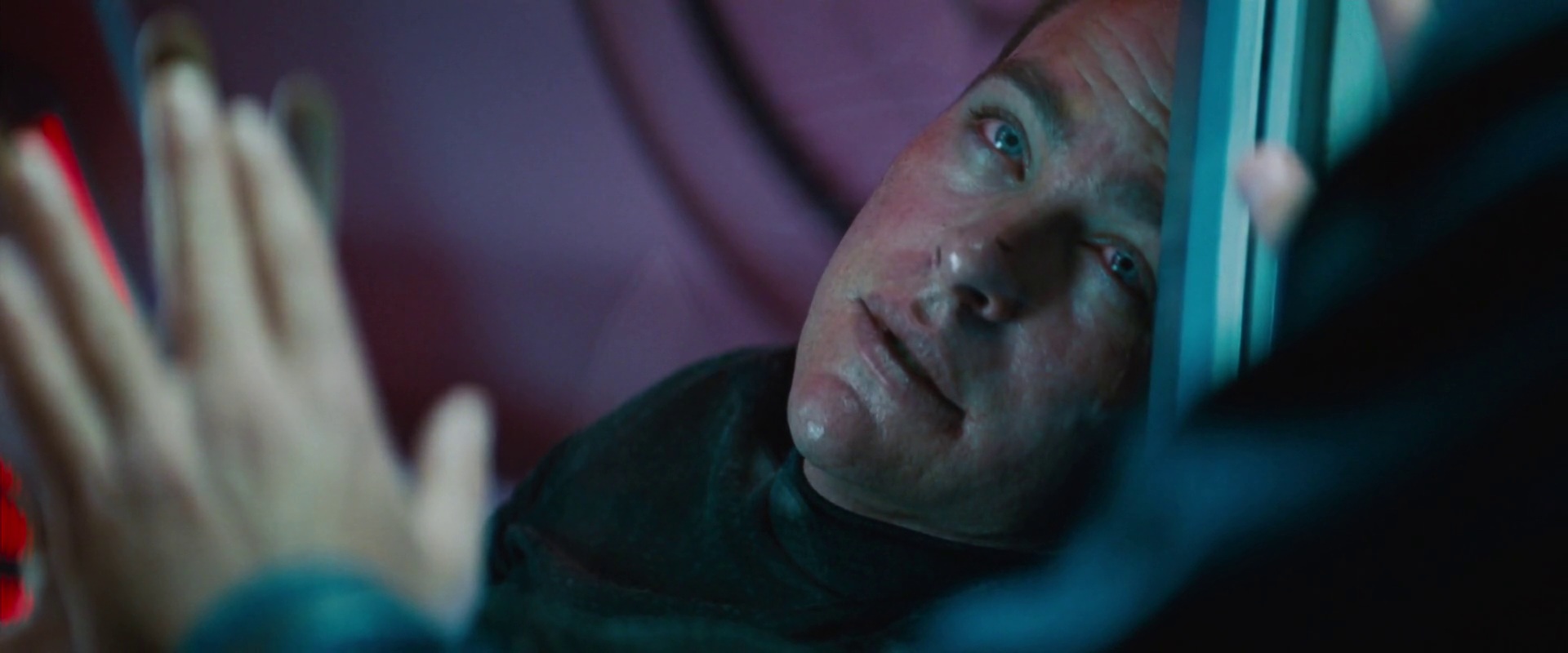 Kirk umírá na ozáření radiací, což sleduje Spock za průhlednými dveřmi.