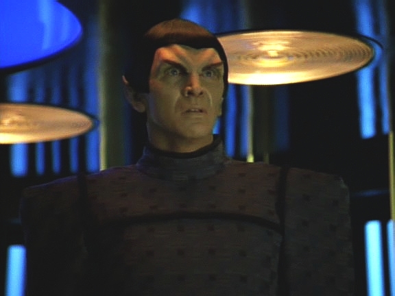 Když se materializuje na plošině transportéru, zjišťuje Tuvok, proč měli při kontaktu problémy: červí díra je trhlinou v prostoru i času. Romulan žije před 20 lety, v roce 2351.