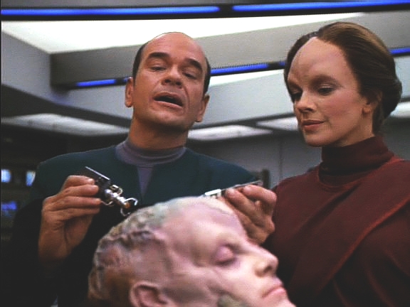 Doktor spolu s ní pracuje na léčbě jejího těla. Použije k tomu B'Elanninu klingonskou DNA, která se před rokem osvědčila. Na výsledky musí několik dní počkat.