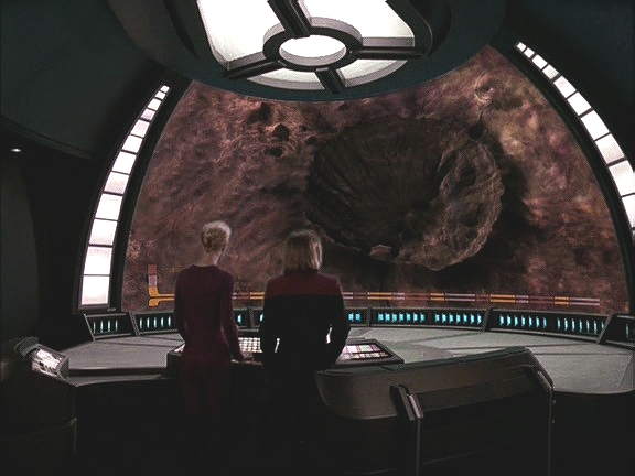 Na palubě se přístroj ptá po svém společníkovi. Kapitán a Sedmá tedy proskenují planetu a objeví obrovský kráter. Jejich návštěvník je mocná zbraň hromadného ničení.
