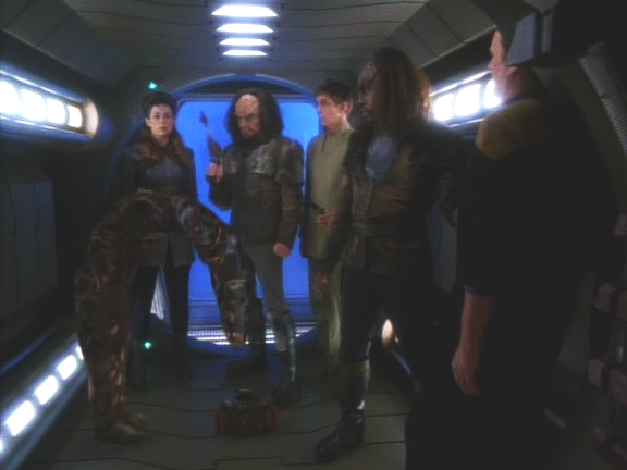 Z doku vyjde čtyřčlenná posádka: Trill, dva Klingoni a žena. Pod hrozbou, že zastřelí O'Briena, donutí Oda vlézt do kufříku, odvedou Bashira z ošetřovny a obsadí OPS.