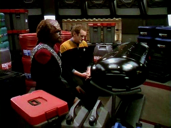 O'Brien, k němuž se překvapivě připojil Worf, drží stráž nad tělem inženýra Munize, kterého smrtelně zranila jem'hadarská střelba.