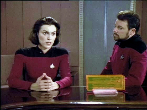 Ro vysvětluje kapitánovi a Rikerovi svůj úkol. Vzhledem k její minulosti se na ni oba muži a zejména Riker dívají velmi kriticky.